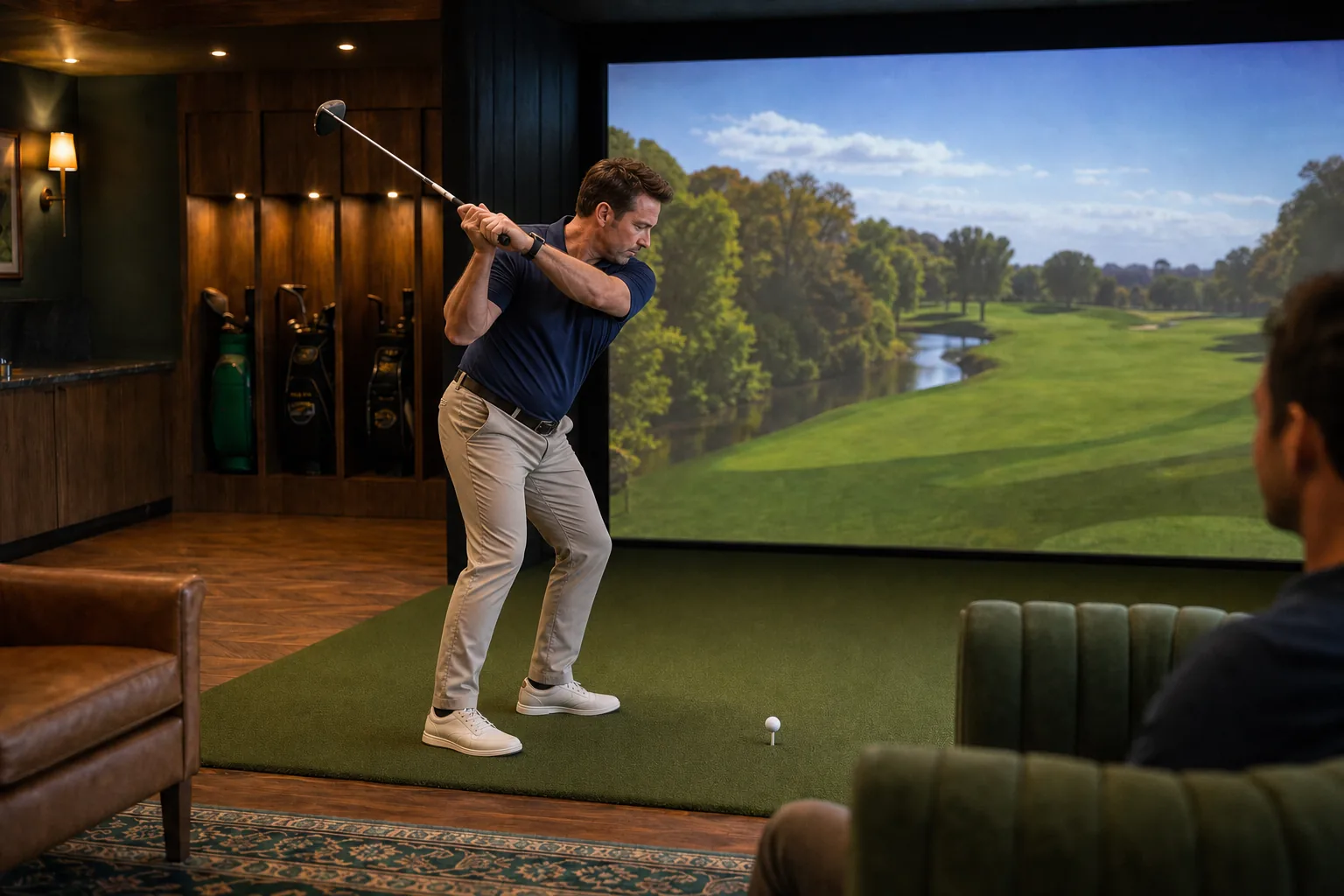A member swings mid-shot in the club's golf simulator suite as another member watches from a lounge chair.