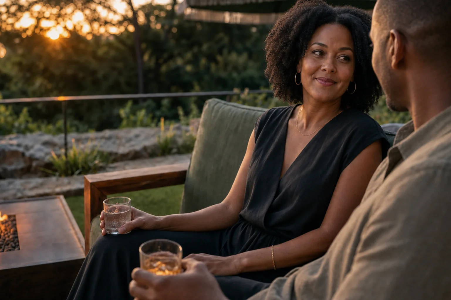 A couple shares a quiet moment on the patio at dusk, drinks in hand near the firepit.